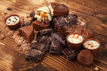 Various yummy chocolate candies on wooden table, sweets