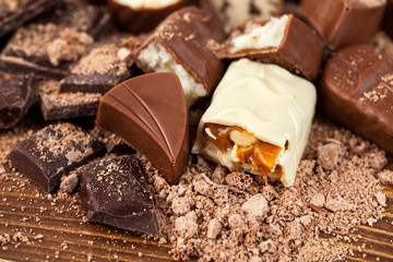 Various yummy chocolate candies on wooden table, sweets