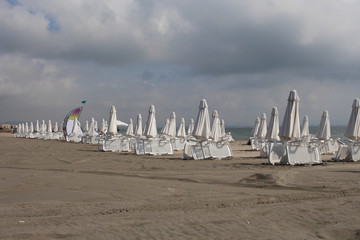 Closed summer umbrellas on the sandy beach.