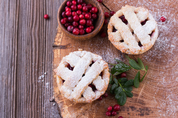 Homemade tartlet with cranberries on wooden table.