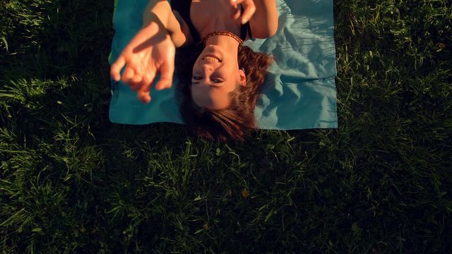 Happy smiling woman lying on the meadow and enjoying while dancing looka at camera. She happy of summer day sunset evening. 4k Ultra HD. Slow motion