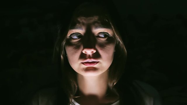 Young girl in the dark is very scared, Hard light at night, a woman panics