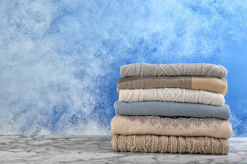 Stack of warm autumn clothes on table. Space for text