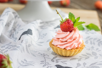 Detail on a Strawberry tart with strawberry whipped cream with one strawberry and mit leaf