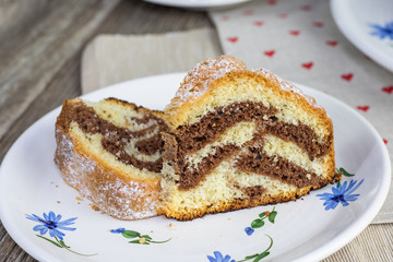 Detail on a slice of Czech traditional marble bundt cake on old ceramic dining set.