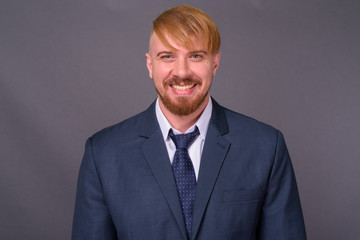 Bearded businessman with blond hair against gray background