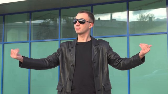 young man in leather jacket and sunglasses standing outdoor and man inviting someone