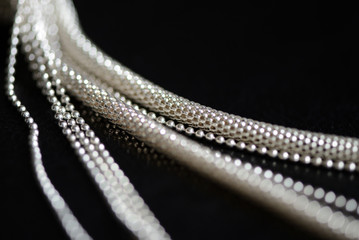 Metal necklace tied in a knot on a dark background close up