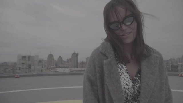 Nice girl goes on the background of the city view. Slow motion, s-log, ungraded