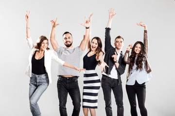 Girls and guys dressed in stylish casual clothes rejoice and have fun on a white background in the studio
