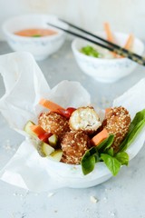 Hot roll of cheese and chicken in breadcrumbs of breadcrumbs and sesame with fresh vegetables and sauces. Delicious food in Asian style Copy space