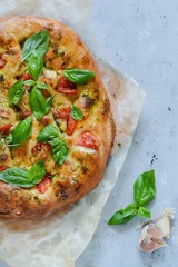 Italian focaccia with tomatoes, pesto sauce, garlic and rosemary. National bread. Copy space
