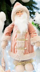 Cute stuffed toy Santa Claus giving a Christmas present. Santa Claus, a bag of presents and Christmas tree.