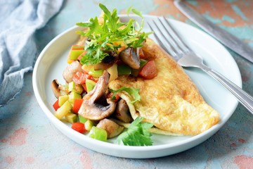 Homemade omelet with mushrooms, vegetables and arugula on a plate. Wonderful healthy breakfast.