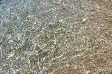Shallow water beach sand pebbles sun reflection