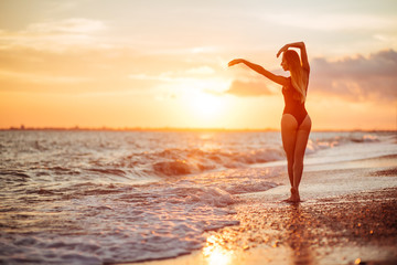 Obraz na płótnie Canvas carefree woman dancing in the sunset on the beach. vacation vitality healthy living concept