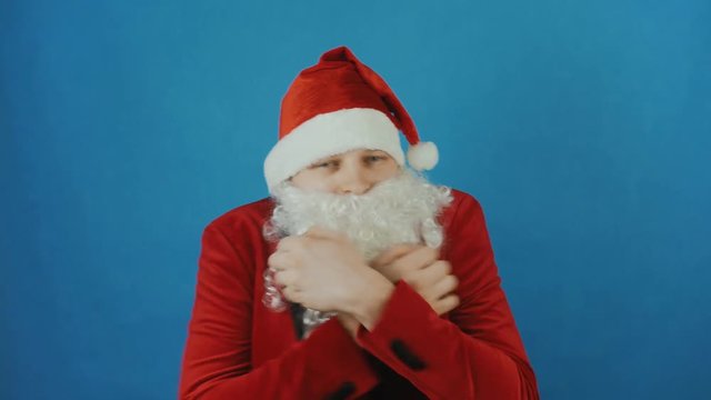 Christmas and New year, man like a Santa trembles or freezes from the cold, on blue background