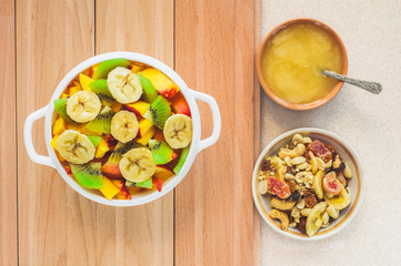 White bowl with fruits, honey and nuts on a wooden table. Top view