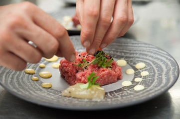 Chef plating gourmet beef tartare appetizer with raw Fassona meat