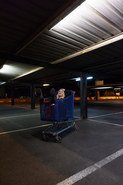 Cheerful woman lying in shopping trolley
