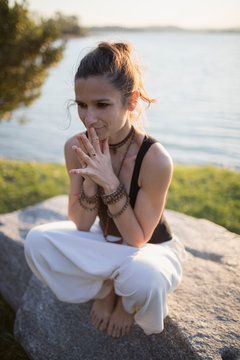Woman sitting on a rock doing mudras