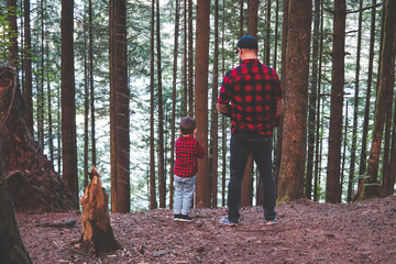 a father and son in matching shirts standing in the forest