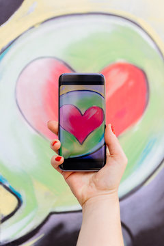 Person taking photo of heart using smartphone