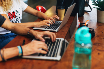 Closeup of young workers using laptops at modern office.
