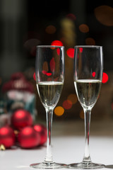 two glasses of champagne, in the background a Christmas atmosphere in red tones, warmth of home