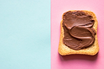 Top view of toasts with chocolate butter on blue pastel and pink pastel background