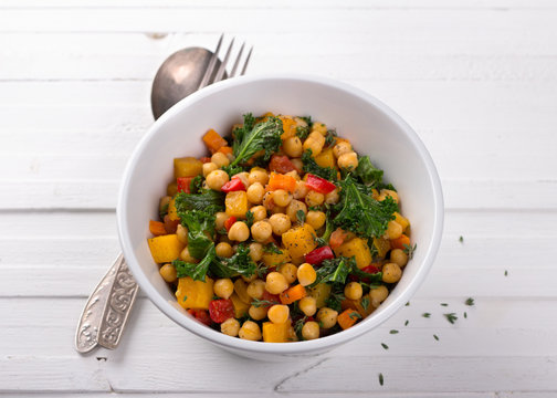 Homemade ragout with pumpkin, carrots, sweet peppers, tomatoes, chickpeas, kale and thyme in a white bowl on a white background. delicious healthy food