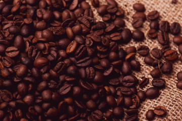 Cafe design, pictures for bars and cafes. Closeup coffee grains on burlap and brown background.