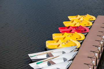Pier with boats and catamarans for a river walk. City river in downtown. Sunny relax weather.