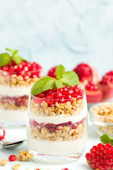 Pomegranate parfait - sweet organic layered dessert with granola flakes, yogurt and ripe fruit seeds.