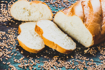 cut Fresh wheat bread with grains around on a wooden table