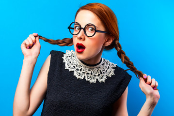 surprised girl in glasses with two pigtails on blue background