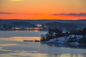 Typical traditional red Scandinavian house at the river leading to the ocean from Turku, a Finnish city at sunrise. View from a ferry while traveling.