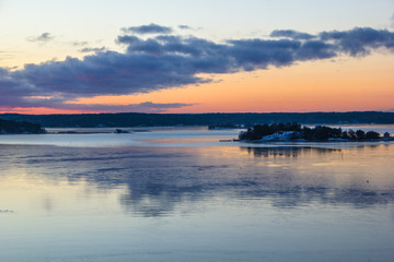 Typical traditional red Scandinavian house at the river leading to the ocean from Turku, a Finnish city at sunrise. View from a ferry while traveling.