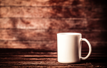 White cup of coffee on wooden table and background