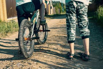 Fototapeta premium Two cropped boys, friends with a bicycle outdoor