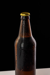 Bottle with soft drinks or alcohol in the ice. On gold caps and a bottle neck are drops of dew. Beer bottle cap close-up macro on black background with clipping path.