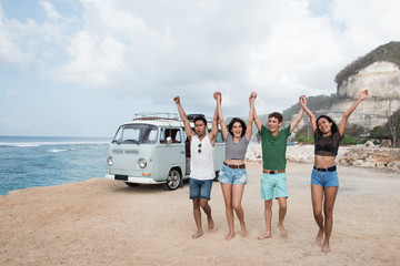 Happy friends walking at beach and rise up hands