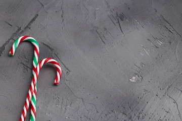 Hard candy canes on grey concrete desk. Christmas decoration. Space for text.