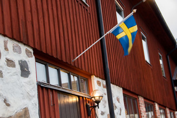 Traditional part of an old, historic and farm building of rural Sweden in Hassleholm during winter with Swedish flag.