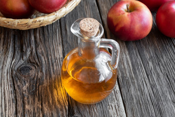 A bottle of apple cider vinegar with fresh apples