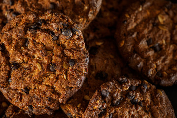 Chocolate chip cookies on rustic dark black background. Stacked chocolate chip cookies on brown napkin. Symbolic image with place for text. Freshly baked. Concept for a tasty snack. Sweet dessert. 