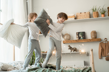 Small boys having pillow fight, doing mess in room