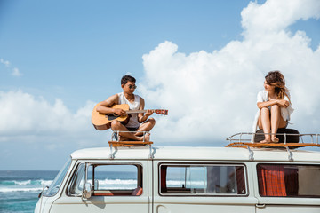 young people on roof of retro styled minivan enjoying time toget