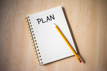 white notebook with notes and wooden desk