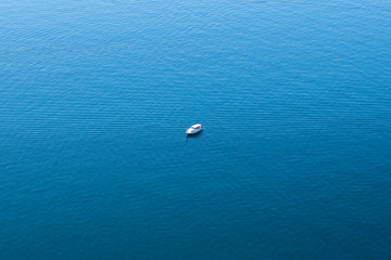 lonely boat in the middle of a calm blue sea